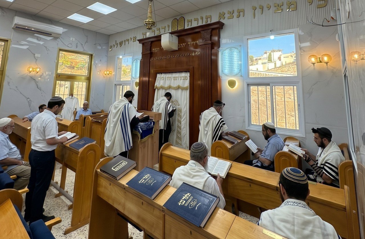 מתפללים ליד ארון הקודש, ספסלי עץ וחלונות מוארים